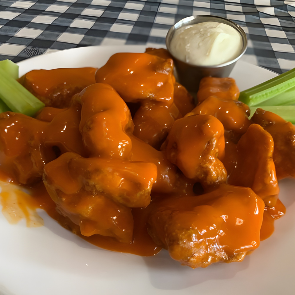 Gino's Pizza and Grill's buffalo wings, coated in orange sauce, with celery sticks and ranch dressing.